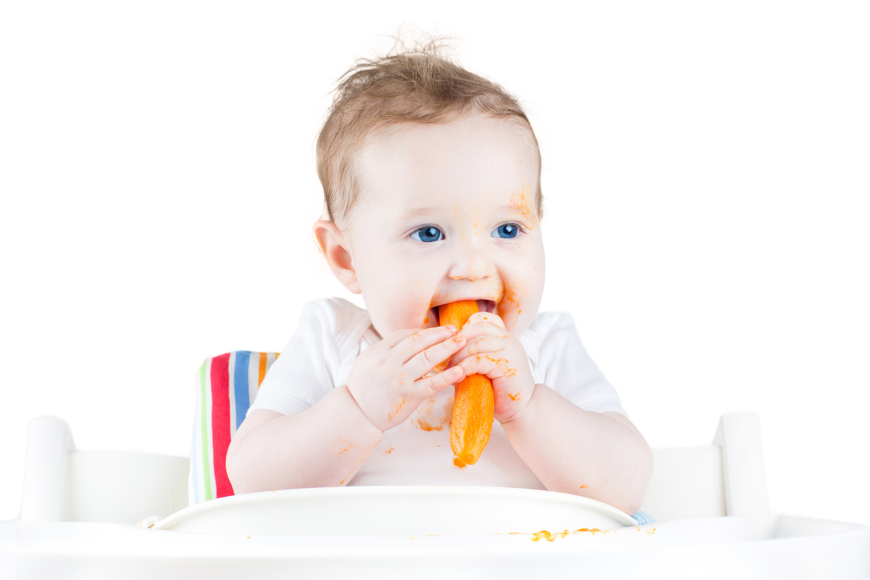 Sweet baby eating her first solid food in white chair